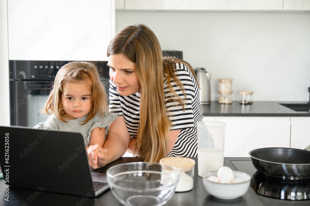Mother and daughter using laptop in kitchen