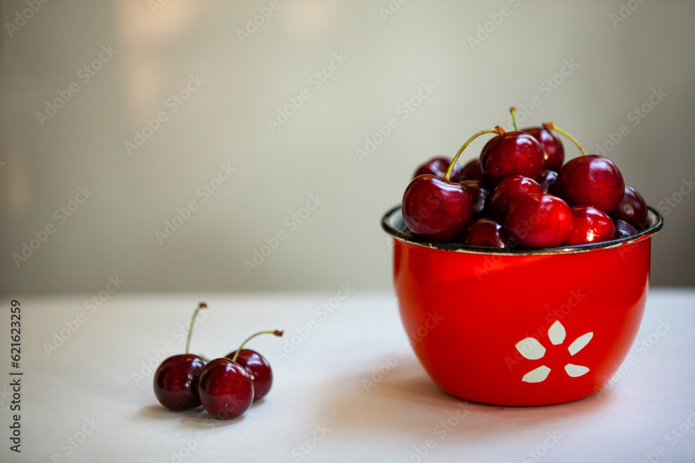 Juicy sweet cherries in a red bowl with copy spase.