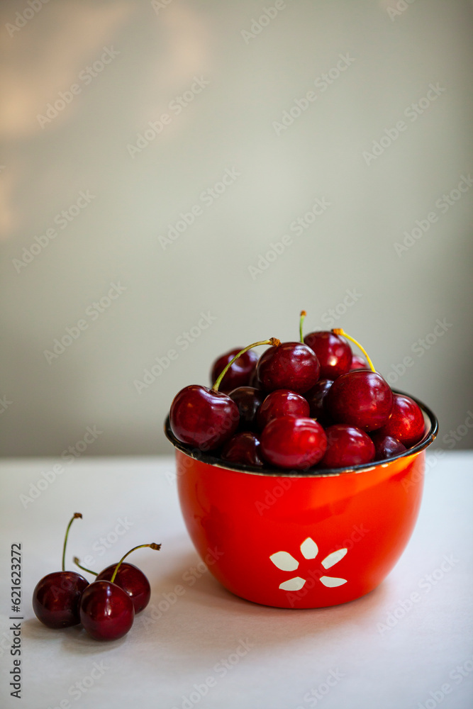 Juicy sweet cherries in a red bowl with copy spase.
