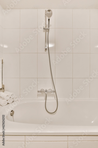 a white bathtub in the corner of a bathroom with a shower head and hand held on it's arm