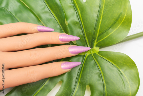 Female hand with long nails with glitter nail polish. Long pink nail design. Woman hand with pink manicure on white background photo