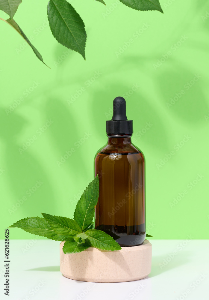 Brown glass bottle with pipette and mint leaves, container for aromatic oils and cosmetics Brown glass bottle with pipette and mint leaves, container for aromatic oils and cosmetics