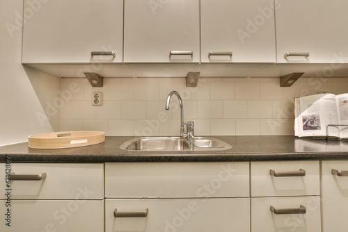 a kitchen with white cupboards and black counter tops on the wall above the sink is a microwave in the corner