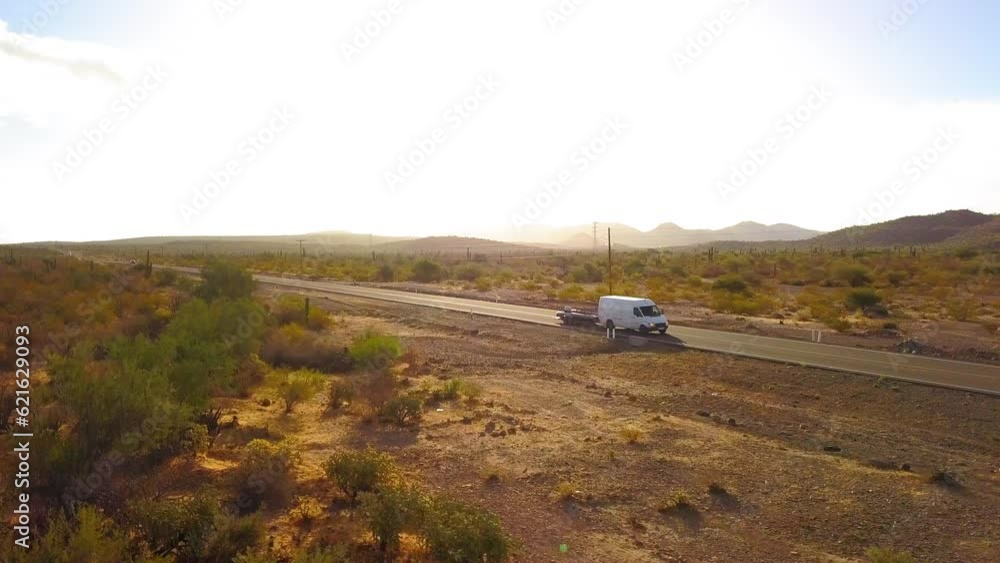 Panning Shot Of Van With Trailer On A Road Amidst Plants Near Mountains Against Sky - Baja California, Mexico Panning Shot Of Van With Trailer On A Road Amidst Plants Near Mountains Against Sky - Baja California, Mexico