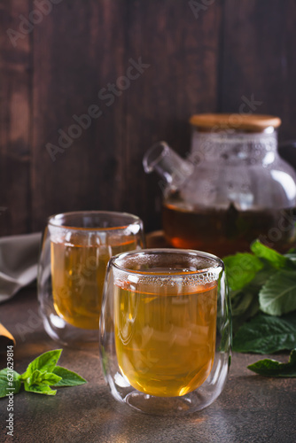 Fresh mint tea in cups and teapot and leaves on the table vertical view