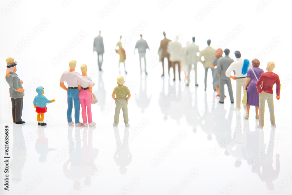 miniature people. little girl with other people stands against the background of other people on a white background. Loneliness and family acceptance in human society. Child care