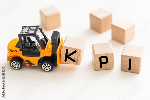 Toy forklift hold wood letter block I to complete word KPI (Abbreviation of Key performance indicator) on white background