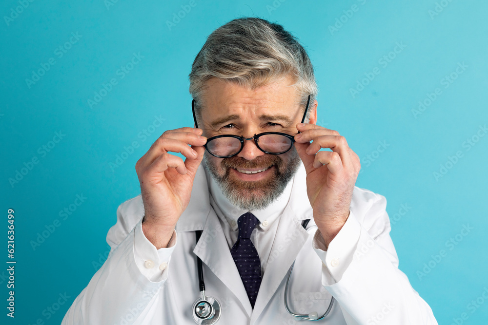 Sceptical and doubtul mature grey-haired bearded doctor adjusting his eyeglasses Sceptical and doubtul mature grey-haired bearded doctor adjusting his eyeglasses