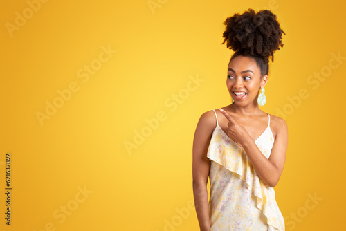 Smiling pretty millennial african american lady pointing finger at empty space
