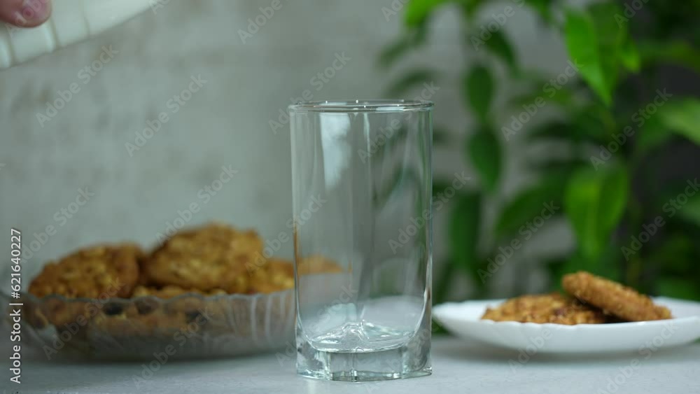 Milk is poured into a glass, morning breakfast milk with oatmeal cookies. slow motion Milk is poured into a glass, morning breakfast milk with oatmeal cookies. slow motion