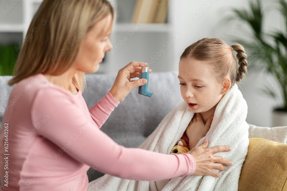 Preventing Attack. Caring mother giving asthma inhaler to sick child at home Preventing Attack. Caring mother giving asthma inhaler to sick child at home