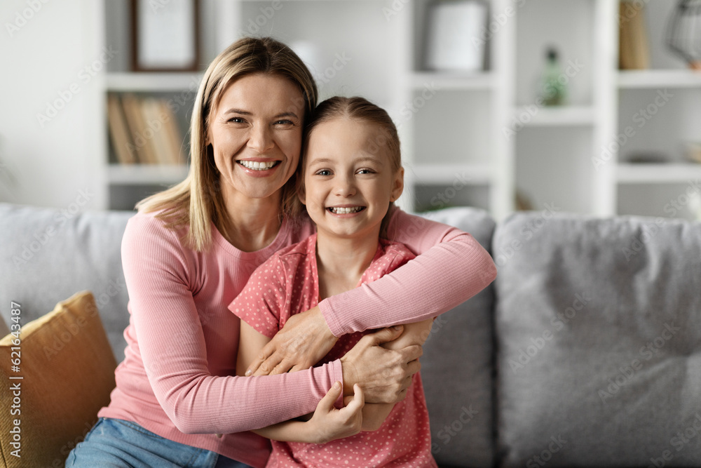Portrait Of Happy Young Mother And Little Daughter Posing In Home Interior