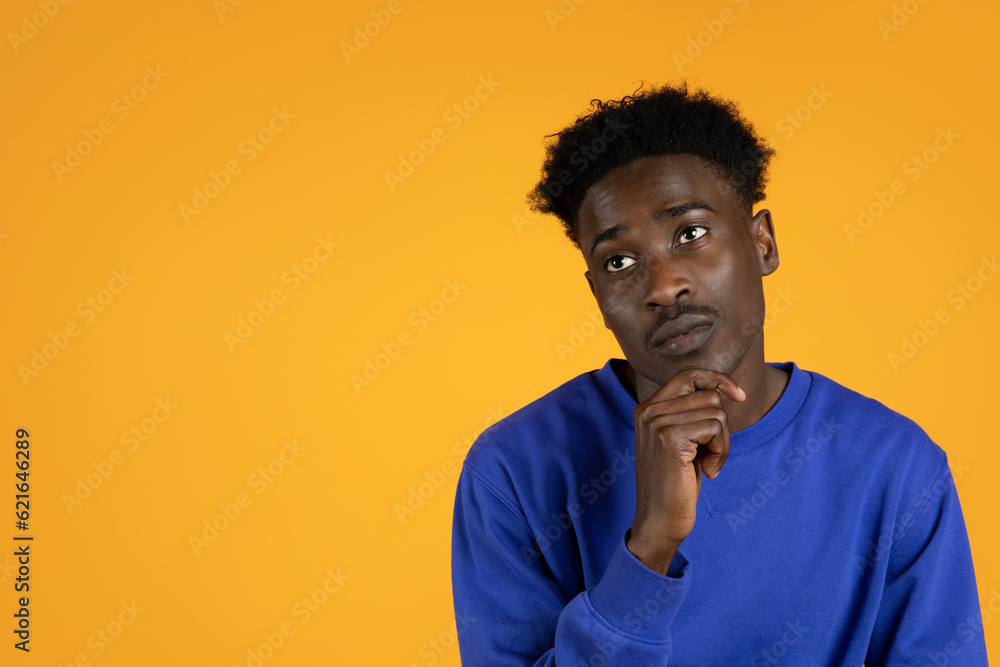 Pensive doubtful young african american guy looking at copy space Pensive doubtful young african american guy looking at copy space