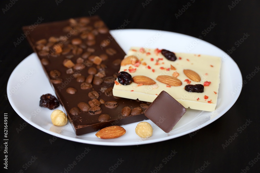 White and dark chocolate with dried raisins, coffee beans and nuts. Tasty dessert in plate on dark wooden table White and dark chocolate with dried raisins, coffee beans and nuts. Tasty dessert in plate on dark wooden table