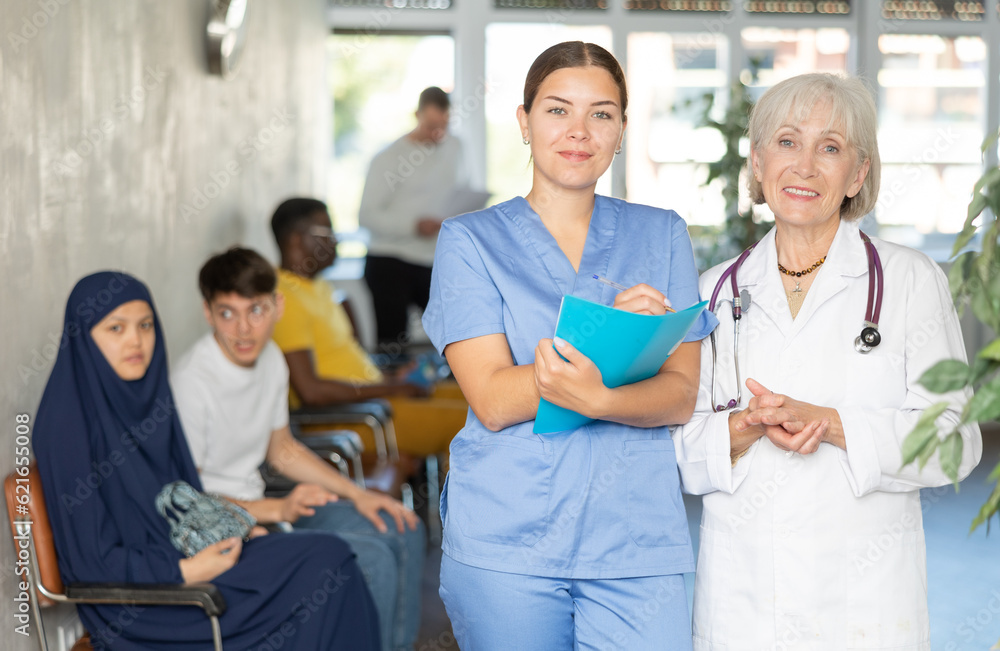 Obraz premium Elderly woman and young woman medics in uniform make notes in notebook at reception