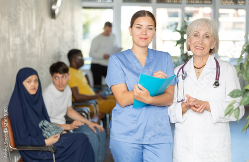 Elderly woman and young woman medics in uniform make notes in notebook at reception