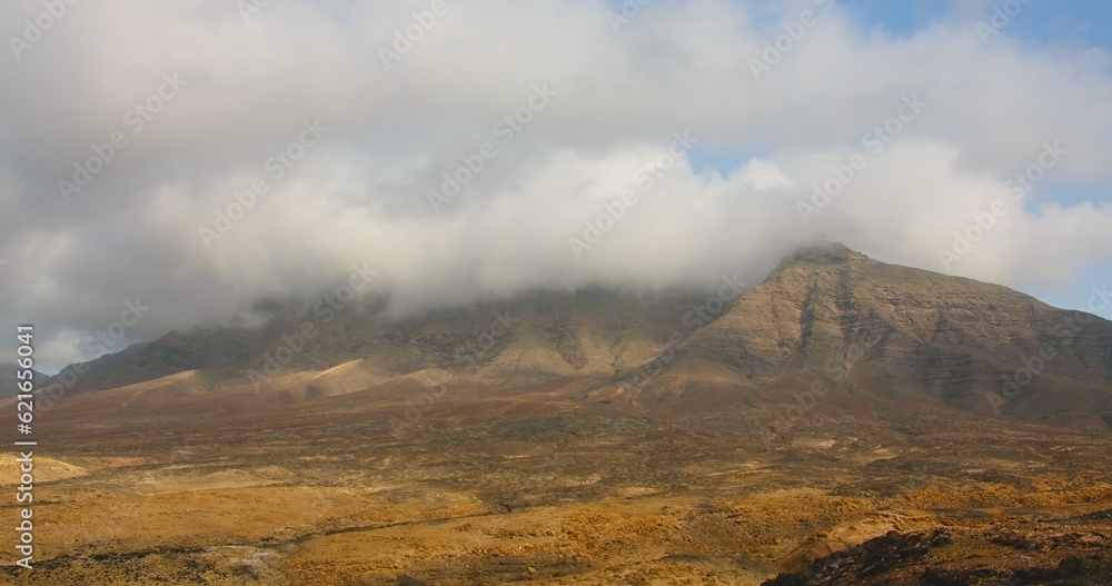 Fototapeta premium Betancuria National Park on Fuerteventura Island, Canary Islands, Spain. Spectacular view of the picturesque desert nature landscape. The tops of the mountains are covered with white clouds, fog
