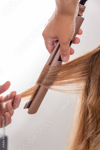 Hair stylist prepares woman makes curls hairstyle with curling iron.