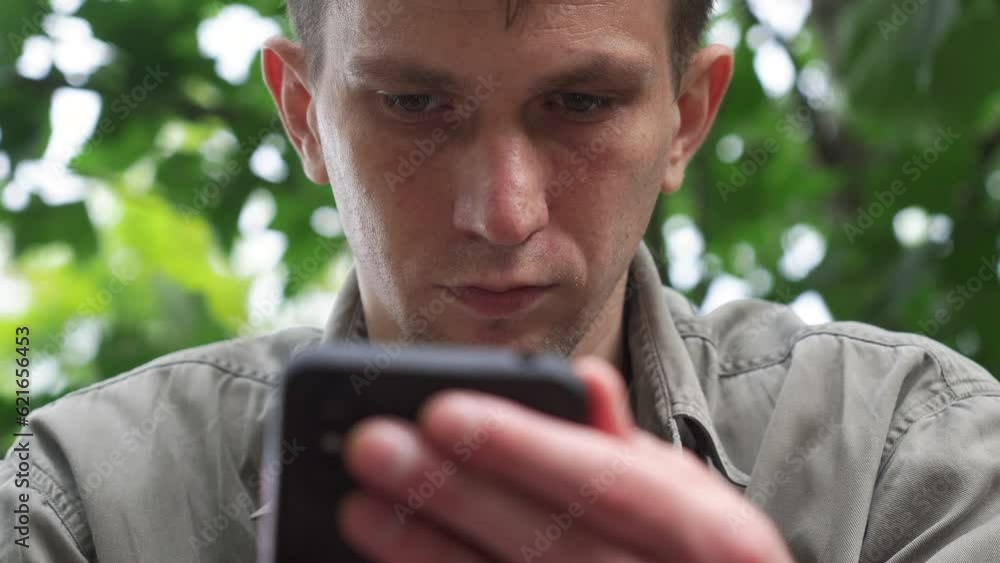 a young man looking at his phone. the park. close-up a young man looking at his phone. the park. close-up