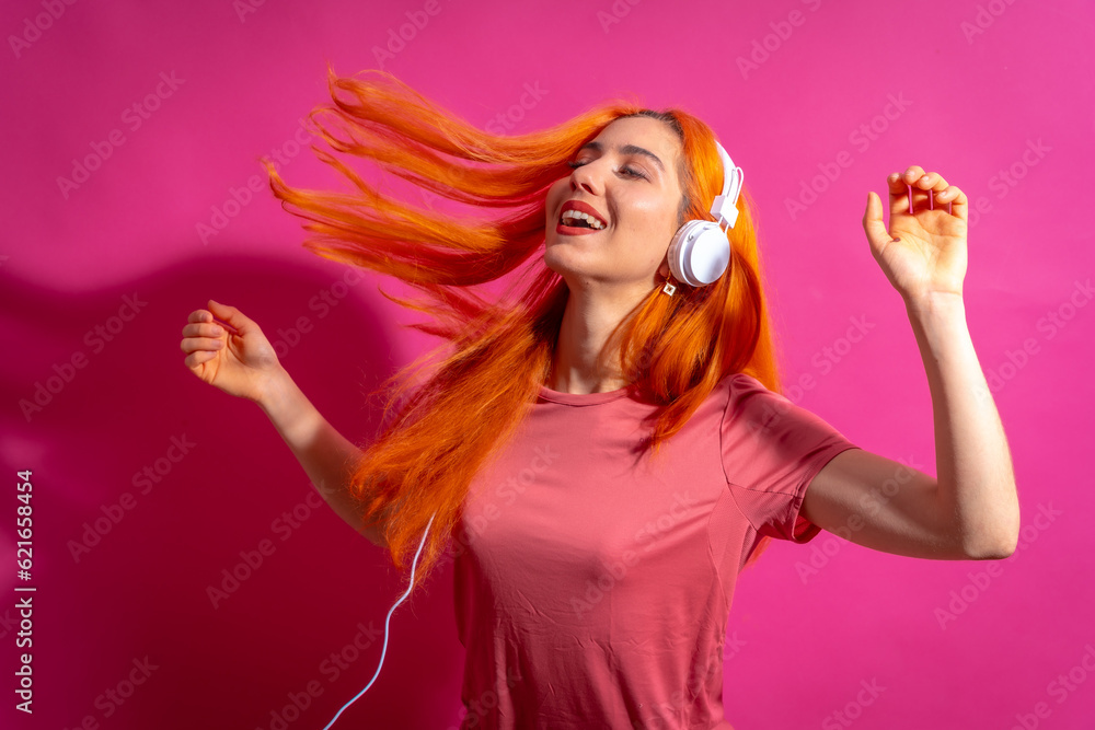 Naklejka premium Redhead woman in studio photography dancing on a pink background, in hard light
