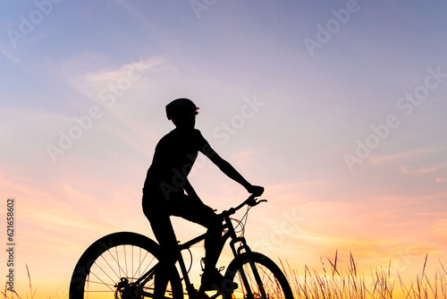 Fototapeta Naklejka Na Ścianę i Meble -  Silhouette of a man riding his mountain bike with sunset in the background