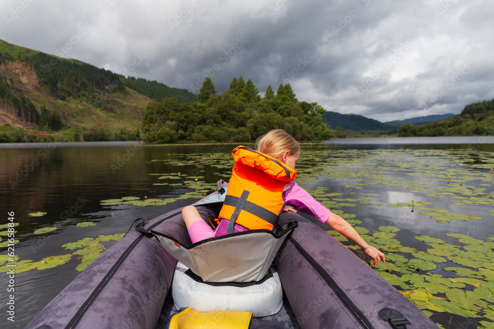 A young girl kayaking on a loch on a summers day in the Scottish Highlands A young girl kayaking on a loch on a summers day in the Scottish Highlands