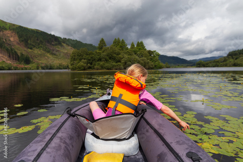 A young girl kayaking on a loch on a summers day in the Scottish Highlands 
