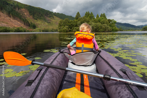 A young girl kayaking on a loch on a summers day in the Scottish Highlands 