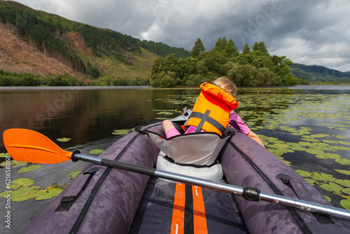 A young girl kayaking on a loch on a summers day in the Scottish Highlands 