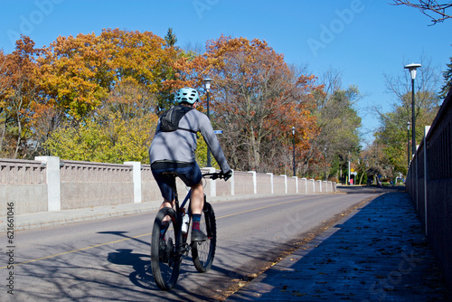 Photography A man riding a bicycle over the bridge with an autumn leaf colour