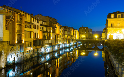 View of lighted Agout river with fringing with old houses and bridges in French town of Castres at dusk photo