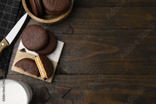 Tasty choco pies, pieces of chocolate and knife on wooden table, flat lay. Space for text