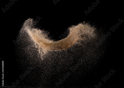 Natural Sand flying explosion, particle dot grain wave explode. Abstract cloud fly. Brown colored sand splash throwing in Air. Black background Isolated