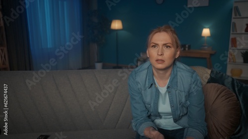 Portrait of a woman sitting on the couch watching TV close up. A woman watches a movie, series, reality show, closely follows the plot, is surprised.