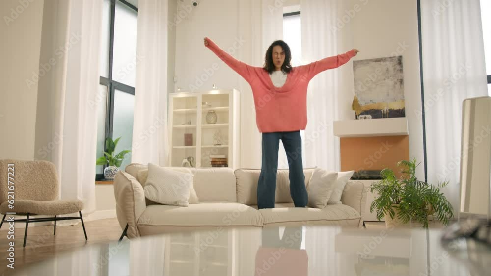 Mixed race woman laughing enjoying newly rented modern flat or urban apartment. Fashion furniture store. Happy young black woman jumping on sofa, feels overjoyed by celebrating move in day to own home Mixed race woman laughing enjoying newly rented modern flat or urban apartment. Fashion furniture store. Happy young black woman jumping on sofa, feels overjoyed by celebrating move in day to own home