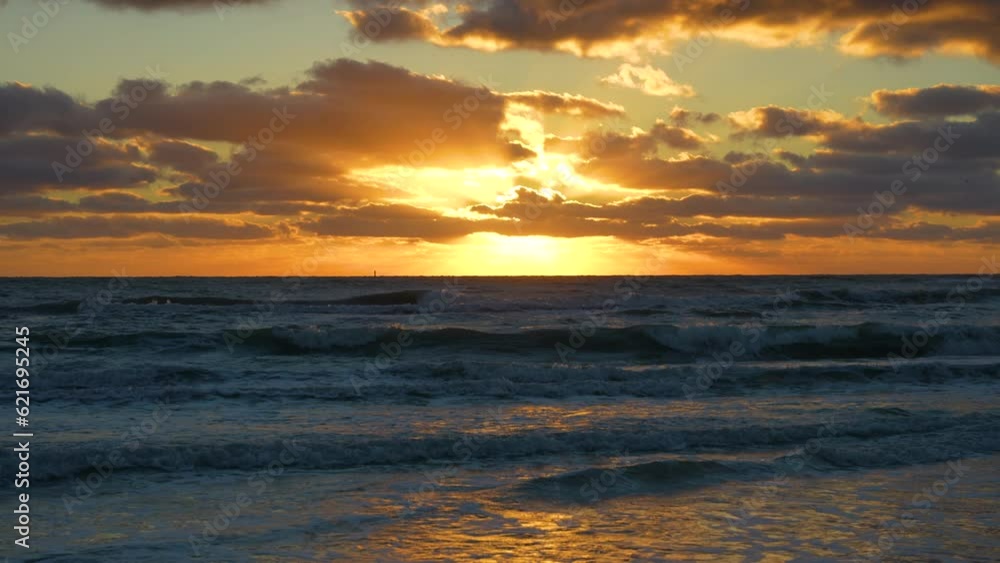 Evening landscape of sea water waves crushing on sandy beach at sunset Evening landscape of sea water waves crushing on sandy beach at sunset