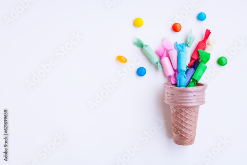 Different kinds of colorful candy out of ice cream cone on gray background, Various candies