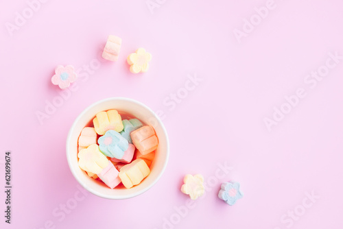 Flower Shaped Marshmallows out of a pink paper cup with white dot on pink background, Multicolored Marshmallows