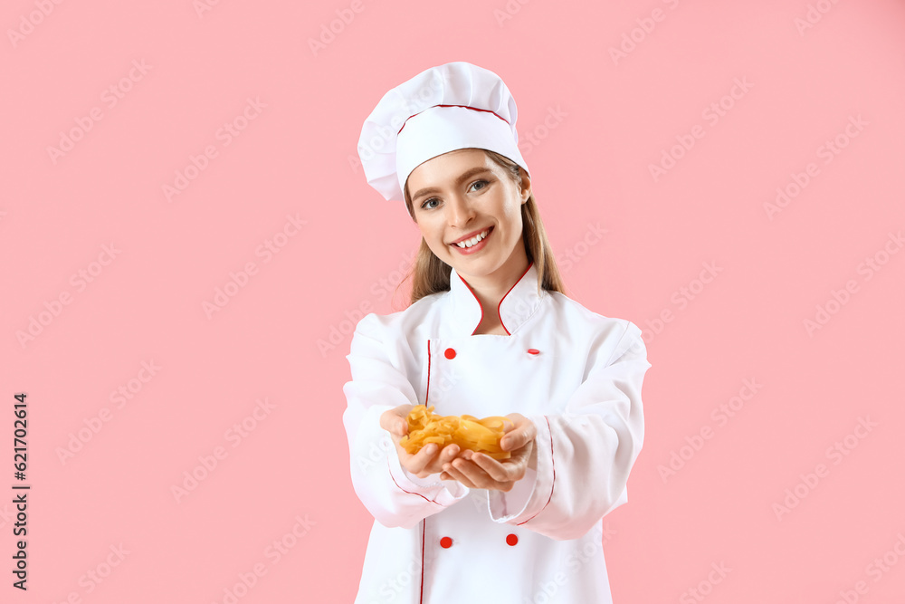 Female chef with raw pasta on pink background Female chef with raw pasta on pink background