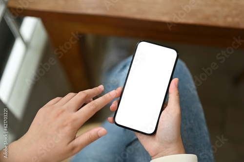 Close-up image of a young Asian woman using her smartphone while sitting at a table