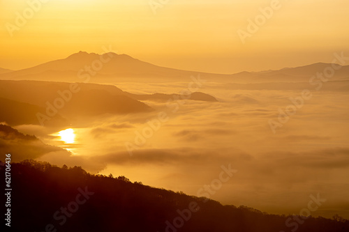 黄金色に霞む朝の湖と山の遠景。