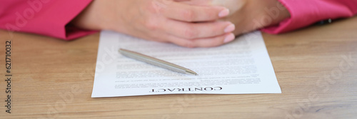 Businesslady sitting at table putting hands on contract agreement