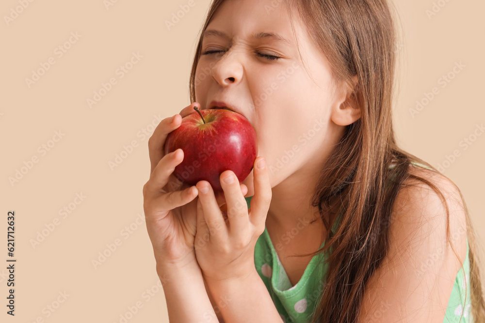Little girl eating apple on beige background, closeup Little girl eating apple on beige background, closeup
