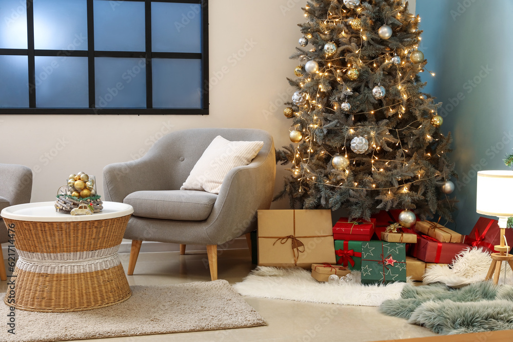 Interior of living room with Christmas tree, gift boxes and grey armchair