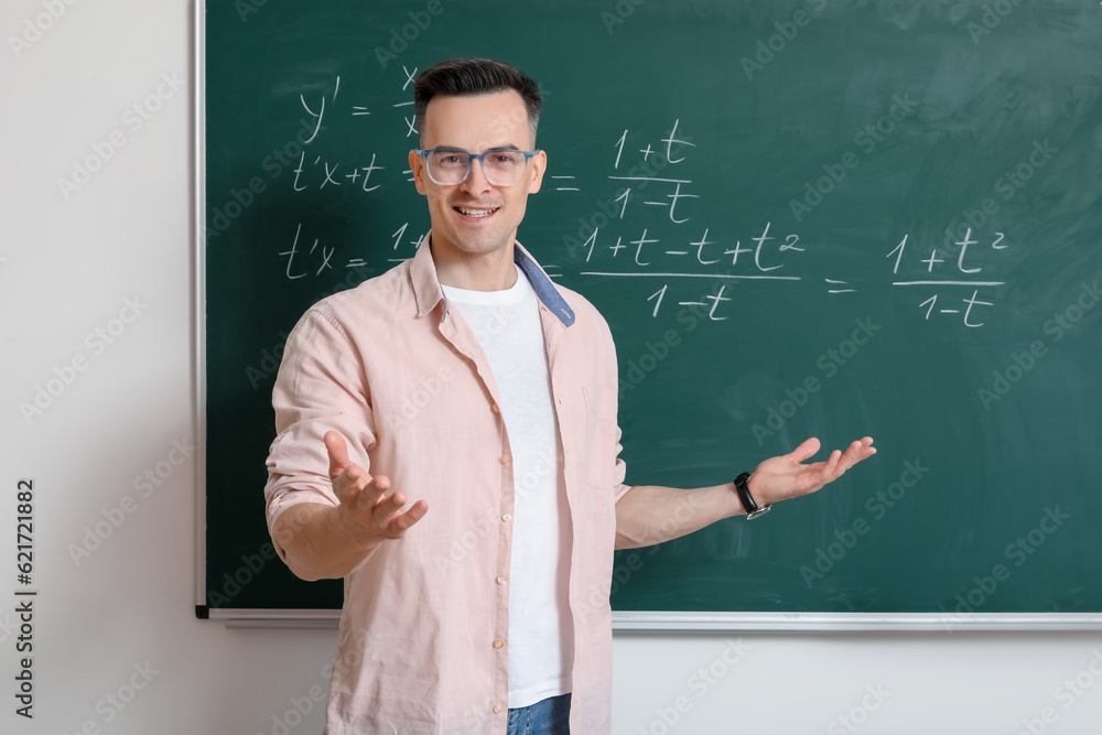 Male Math teacher near chalkboard in classroom Male Math teacher near chalkboard in classroom