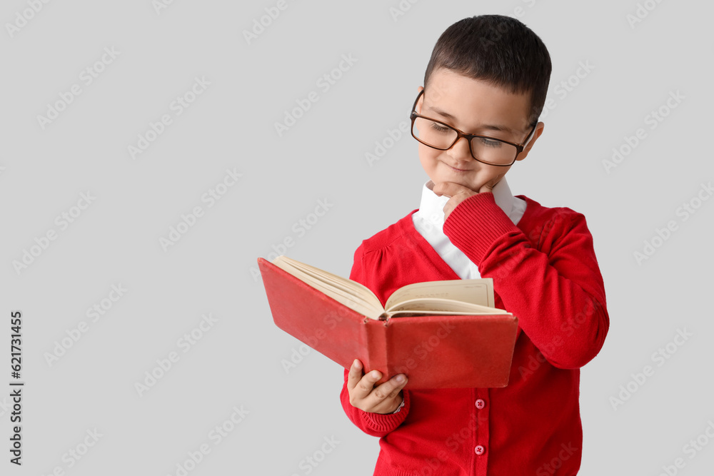 Little schoolboy with book on grey background Little schoolboy with book on grey background
