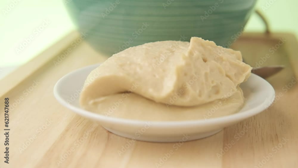 hummus on a small plate rotating on wooden table. Green Background. hummus on a small plate rotating on wooden table. Green Background.