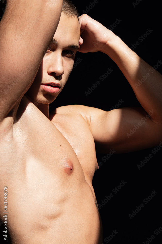 A young attractive guy with a handsome body posing under the sun in the studio.