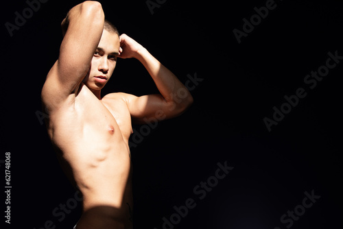 A young attractive guy with a handsome body posing under the sun in the studio.