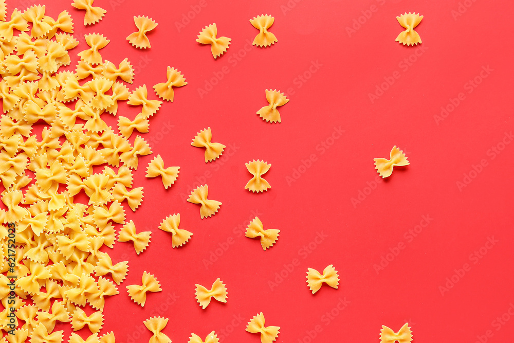 Scattered farfalle pasta on red background